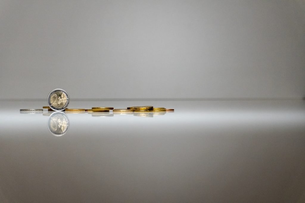a-stack-of-coins-sitting-on-top-of-a-reflective-surface-8f34ux4oai
