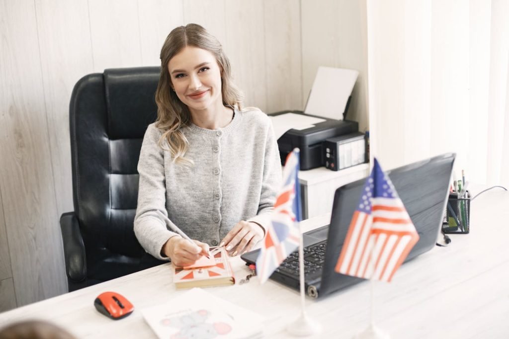 Smiling professional woman at desk with British and American flags, conveying international business.